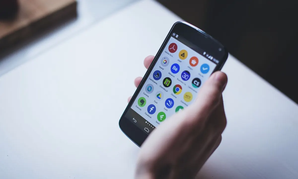 Hand hält ein Smartphone mit App-Symbolen